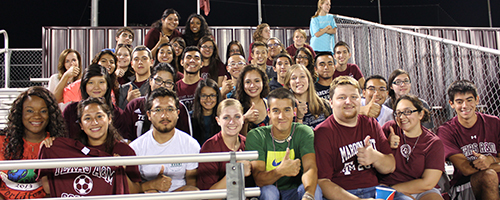 GTF scholars posing together while attending large community meeting at an A&M sports game.